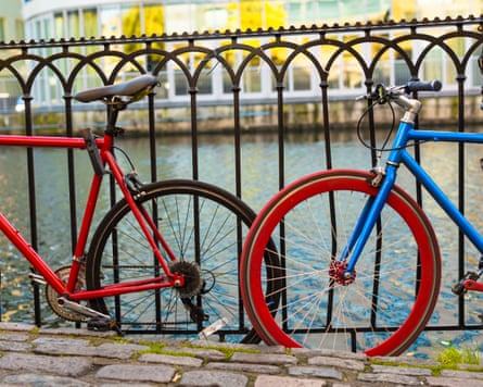Bikes at river bank. Two bikes, red and blue, leaning and locked on the fence at the river bank.