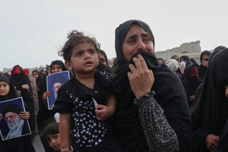 A woman holding a child weeps at a funeral