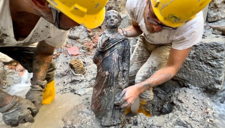 Two archaeologists holding a statue of a boy.