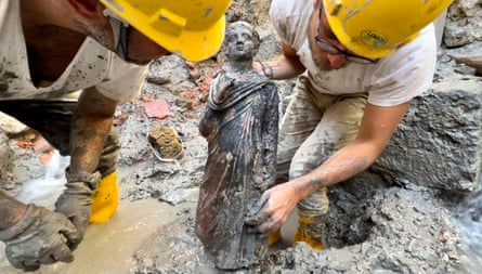 Two archaeologists hold a statue of a boy.