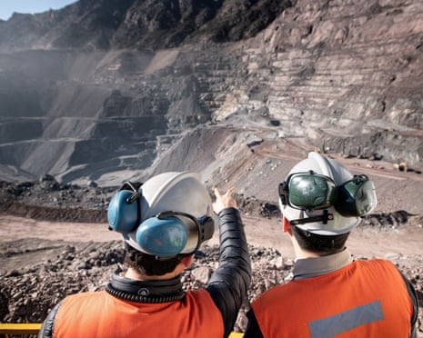 Two men in orange hi-viz vests and helmets stand at Anglo American's El Soldado copper mine in Chile
