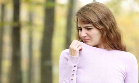 A young woman sniffing her top with a look of disgust
