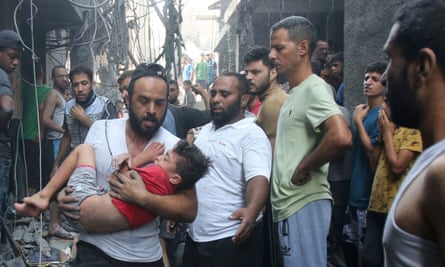 A Palestinian man rushes past rubble carrying a child in his arms, following an Israeli military strike in Gaza City on October 12, 2023.