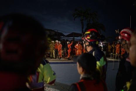 The rescuers observe silence in the hope of hearing sounds from survivors.