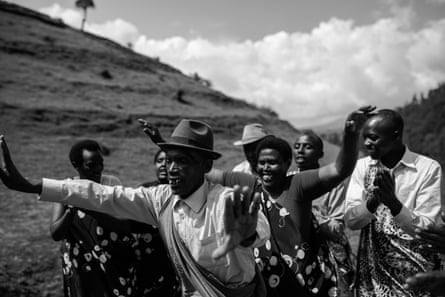 Groupe de sept personnes, hommes et femmes, portant un mélange de vêtements traditionnels et occidentaux, applaudissant et chantant