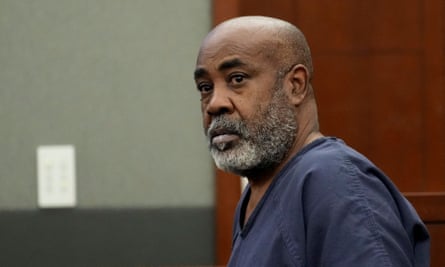 Older black man, bald head, gray full beard, dark blue prison top.