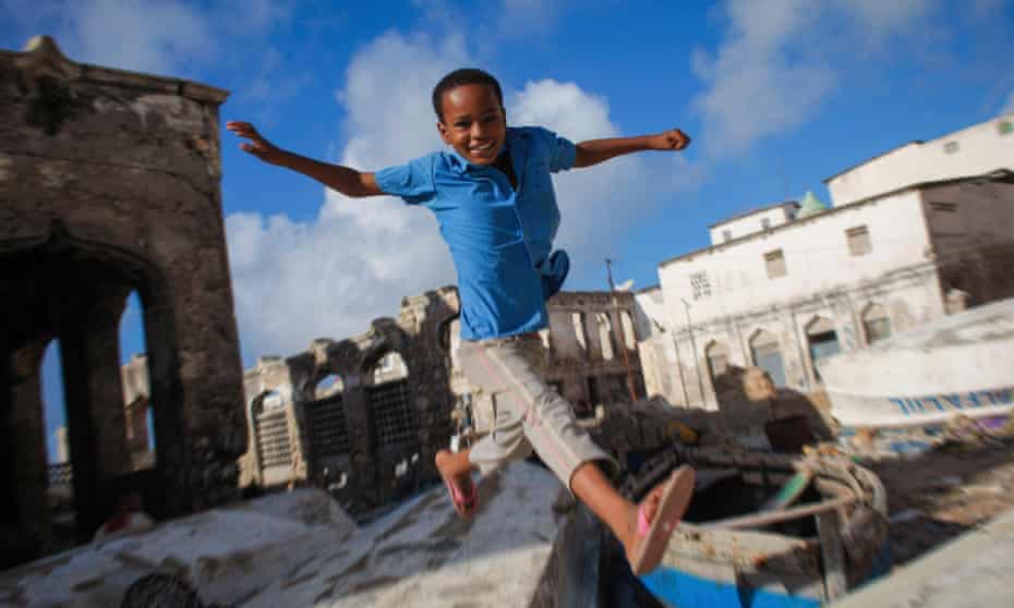 A Somali boy jumps between old fishing boats near Mogadishu’s harbour