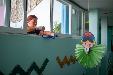 A woman collects dust samples on a window ledge of a school.