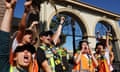 Union members raise their fists outdoors in front of an arched building.