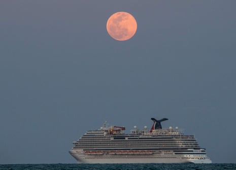 cruise ship sailing under a pink full moon