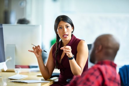 A man and woman talking while seated in an office.