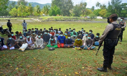 Polisi Indonesia memantau sekelompok orang Rohingya saat mereka mendarat di Pantai Indira Batra di Desa Latong, Provinsi Aceh, Indonesia.