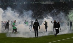 TOPSHOT-FBL-FRA-LIGUE1-LIGUE2-PLAY-OFF-SAINT-ETIENNE-AUXERRE-FAN<br>TOPSHOT - Saint-Etienne's fans invade the pitch through smoke after being defeated at the end of the French L1-L2 play-off second leg football match between AS Saint-Etienne and AJ Auxerre at the Geoffroy Guichard Stadium in Saint-Etienne, central-eastern France on May 29, 2022. (Photo by JEAN-PHILIPPE KSIAZEK / AFP) (Photo by JEAN-PHILIPPE KSIAZEK/AFP via Getty Images)