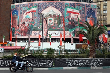 people drive past a billboard featuring a portrait of the late supreme leader Ayatollah Ali Khamenei in Tehran