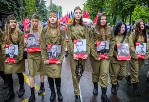 Women carry photographs of war veterans while walking in a line down the street