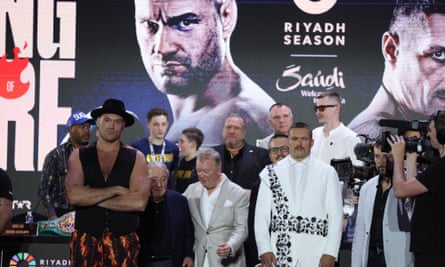 Oleksandr Usyk and Britain’s Tyson Fury on a crowded stage behind a giant backdrop of the two boxers