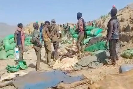 Men inspect an airstrike site among green sacks at a Sudan gold mine