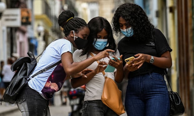 Women use their phones on the street in Havana, Cuba, 14 July 2021.