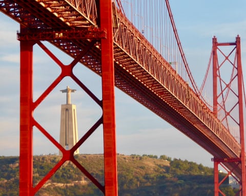 Lisbon, Portugal. 'While in a cafe close to the stunning 25 de Abril Bridge, clouds cleared to reveal this view of the iconic Christo Rei statue in Almada, across the River Tagus'.