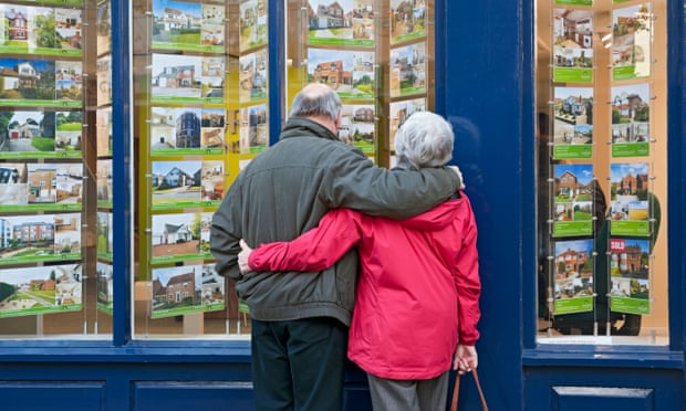 An older couple look in an estate agent windows