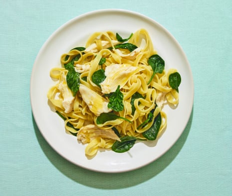 Chicken, spinach and olive oil with pasta on white plate against blue/green background