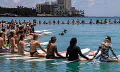 People hold hands during a community paddle out for those affected by the Maui fires in Honolulu, Hawaii, on 19 August 2023.