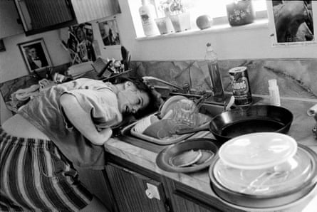 Jeune femme se rinçant les cheveux dans un évier de cuisine