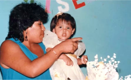 Old snapshot of an Indigenous South American woman holding a small girl in a white dress at a celebration
