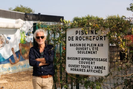 Le Gall stands outside the entrance to the Louet municipal swimming pool net to a sign in French