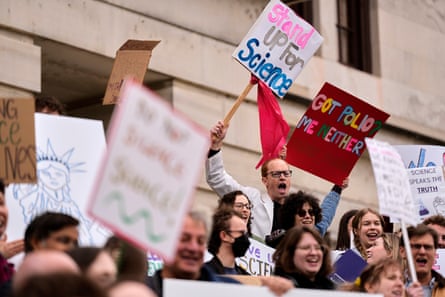 people hold signs at a rally