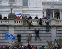 People climb a wall and wave Trump flags.