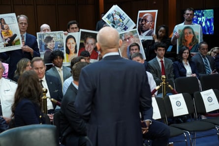 a man faces people holding up photographs of their deceased loved ones