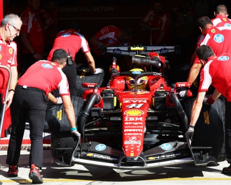 Team members push Lewis Hamilton's Ferrari into the garage with him inside the car