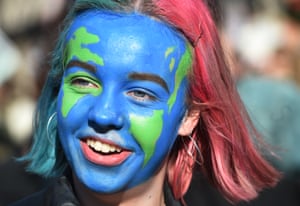 A woman with her face painted to look like the Earth attends the protest