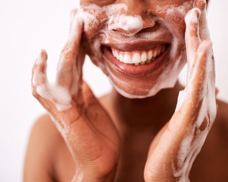 A woman washing her face against a white background