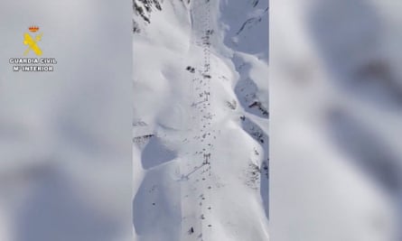 An aerial view of people gathered around the collapsed chairlift at the Astún ski resort.