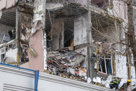 Ukrainian rescuers look through rubble inside a damaged residential building in Kyiv.