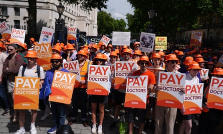 Junior doctors protest outside Downing Street wearing orange hats and holding banners that say ‘pay restoration for doctors’