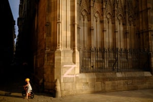 A child rides a bike next to the cathedral wall in Barcelona, painted with the letter Z, the symbol of the Russian military