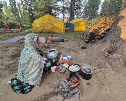 An older southbound Asian female sits stirring a cookware connected an outdoors clay fireplace