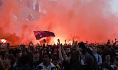 Soccer fans wave an Australian flag and release flares