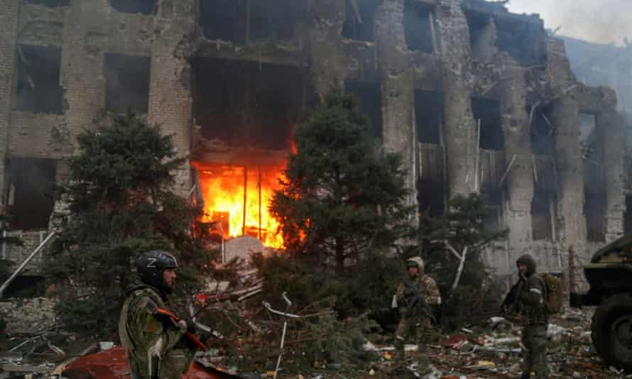 Russian troops stand in front of the destroyed administration building of Azovstal iron and steel works.