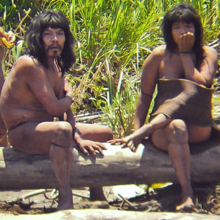 Members of the Mashco Piro tribe, a man and a woman, sitting on a log at an undisclosed forest location near the Manu national park in south-eastern Peru.