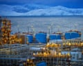 A liquefied natural gas facility in front of the sea and with snow-capped mountains in the background