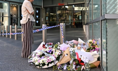 A person looks at floral tributes, at the entrance to Westfield Bondi Junction shopping centre in Sydney, for the victims of the fatal stabbings