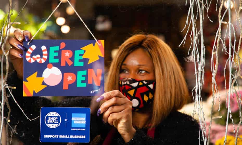 Janet Edwards hangs a festive We’re Open sign designed by artist Timothy Hunt in the window of her flower shop in south London to celebrate the American Express Shop Small campaign and welcome shoppers back to the high street as England’s second lockdown lifts.