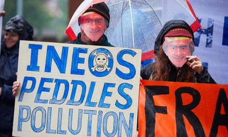 Two protesters wearing Jim Ratcliffe face masks and holding a placard reading 'Ineos peddles pollution'