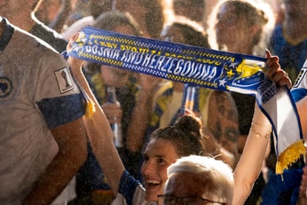 a woman holds up a scarf that says Bosnia and Herzegovina