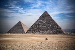 A man rides a horse in front of the pyramids in Giza, Egypt