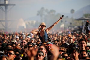 A woman sitting on a person’s shoulders looks out over the rest of the crowd